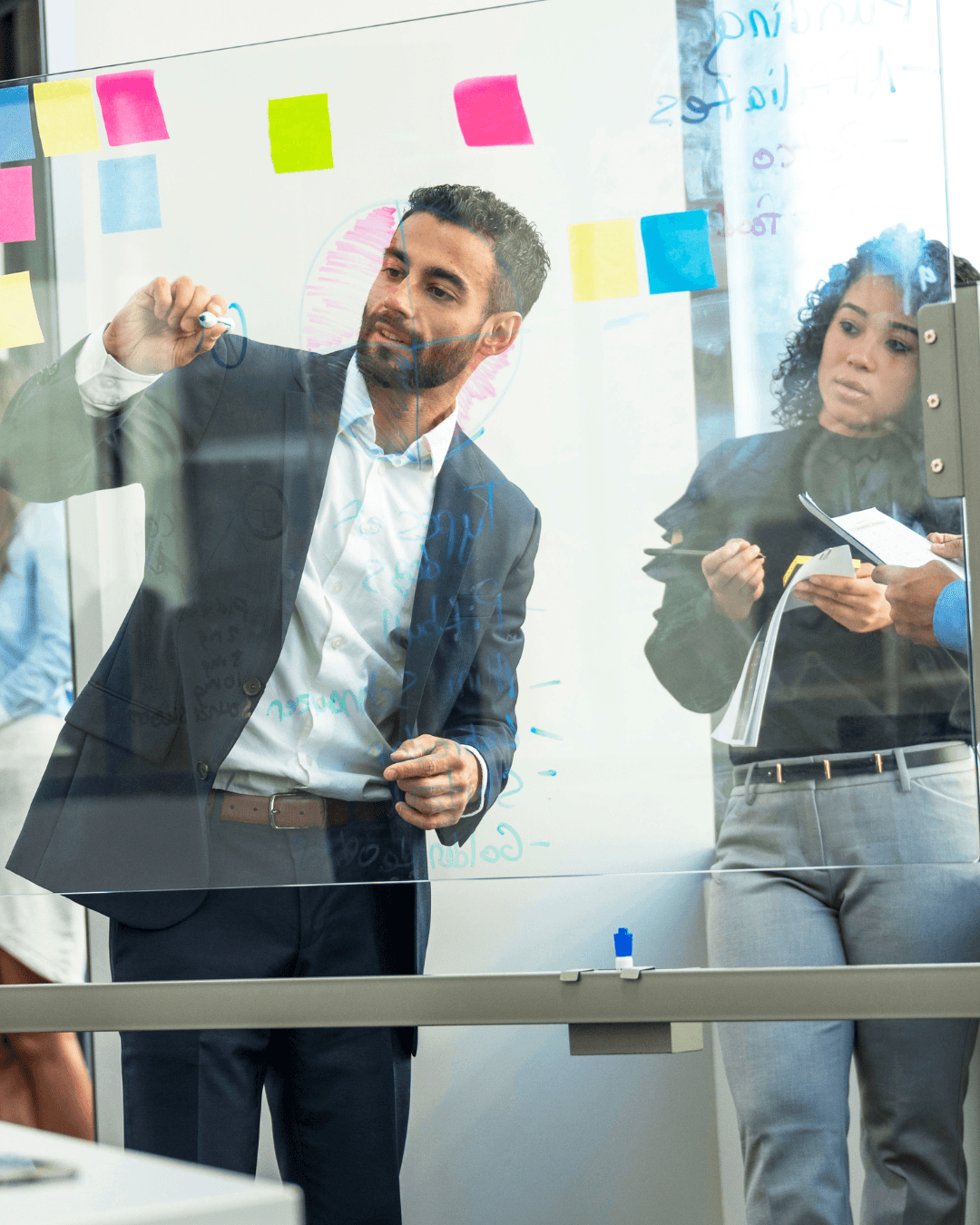 Professionals mapping workforce operations and process priorities on a glass board